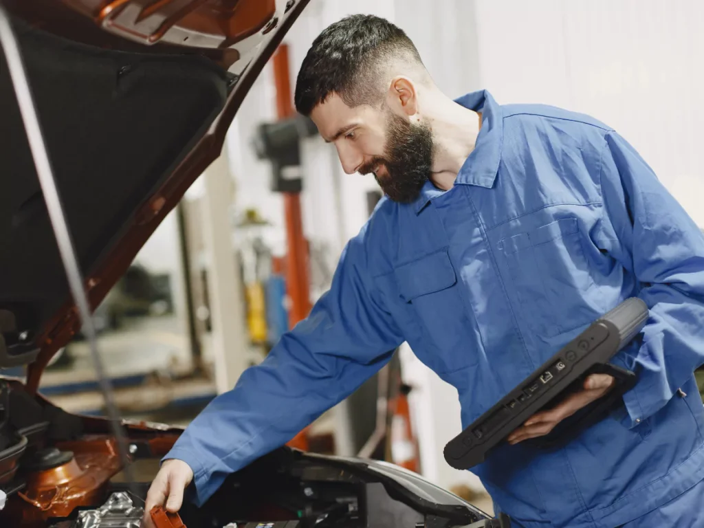 A professional conducting a mobile car check in Houston, using a diagnostic tool on a car's engine.