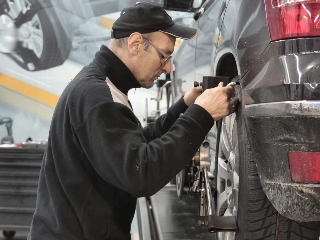 A detailed pre-purchase car inspection in Creekside Estates South, with a mechanic checking the suspension and tire area.