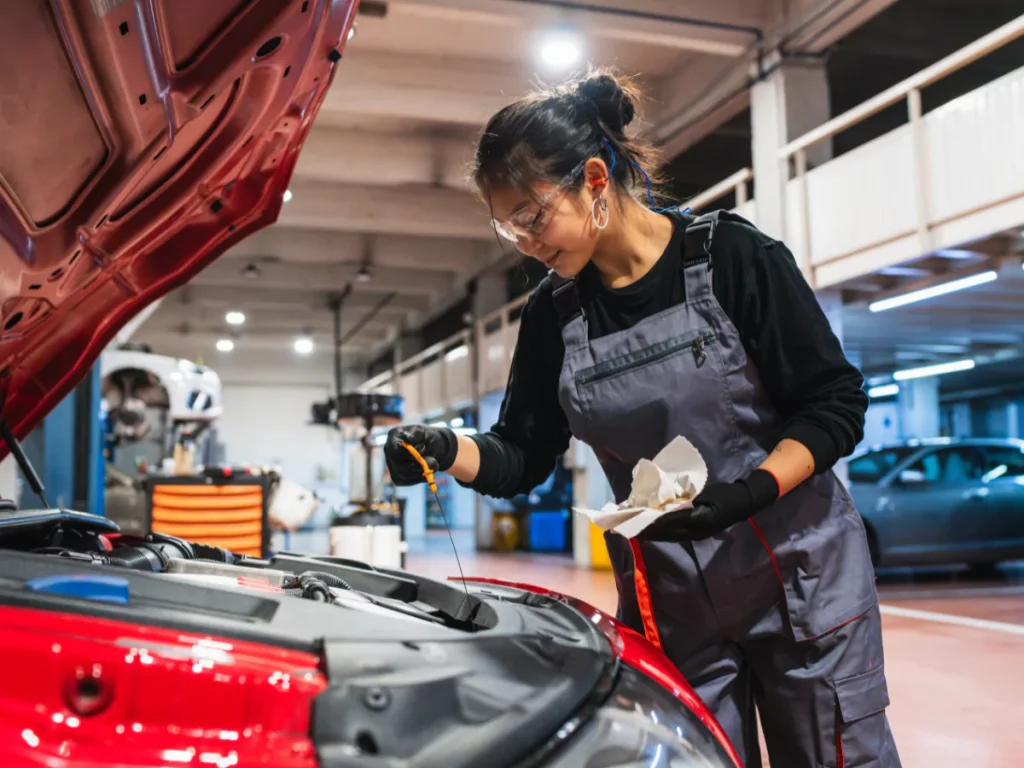 A certified female technician in a garage, performing a pre-purchase car inspection in Beltway Crossing Business Park.