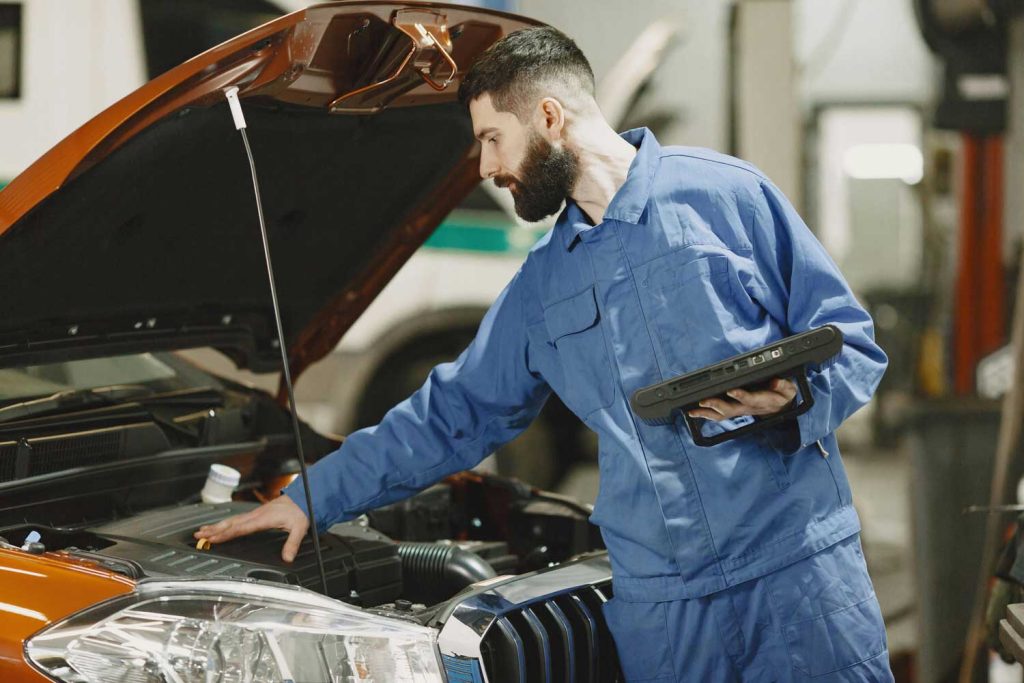 Mechanic testing a blue car's brakes during Pre Purchase Used Car Inspection Houston, with diagnostic tools and a lift.