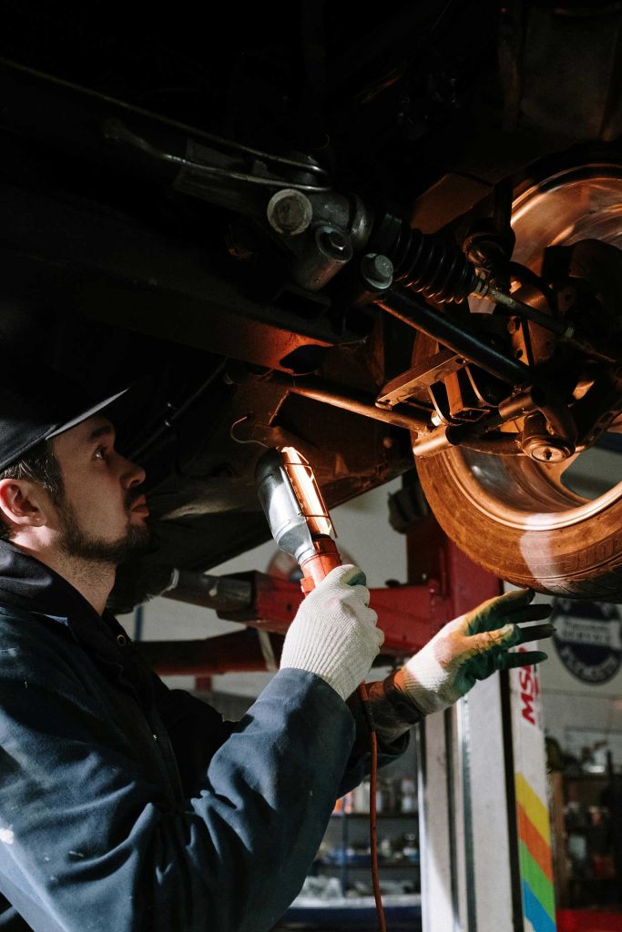 Technician examining a white car's engine during Pre Purchase Used Car Inspection Houston, with tools and a checklist nearby.