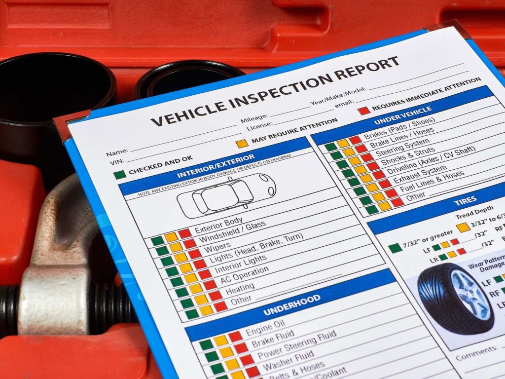 Vehicle inspection report checklist for used auto inspection in Houston on a red toolbox with tools.