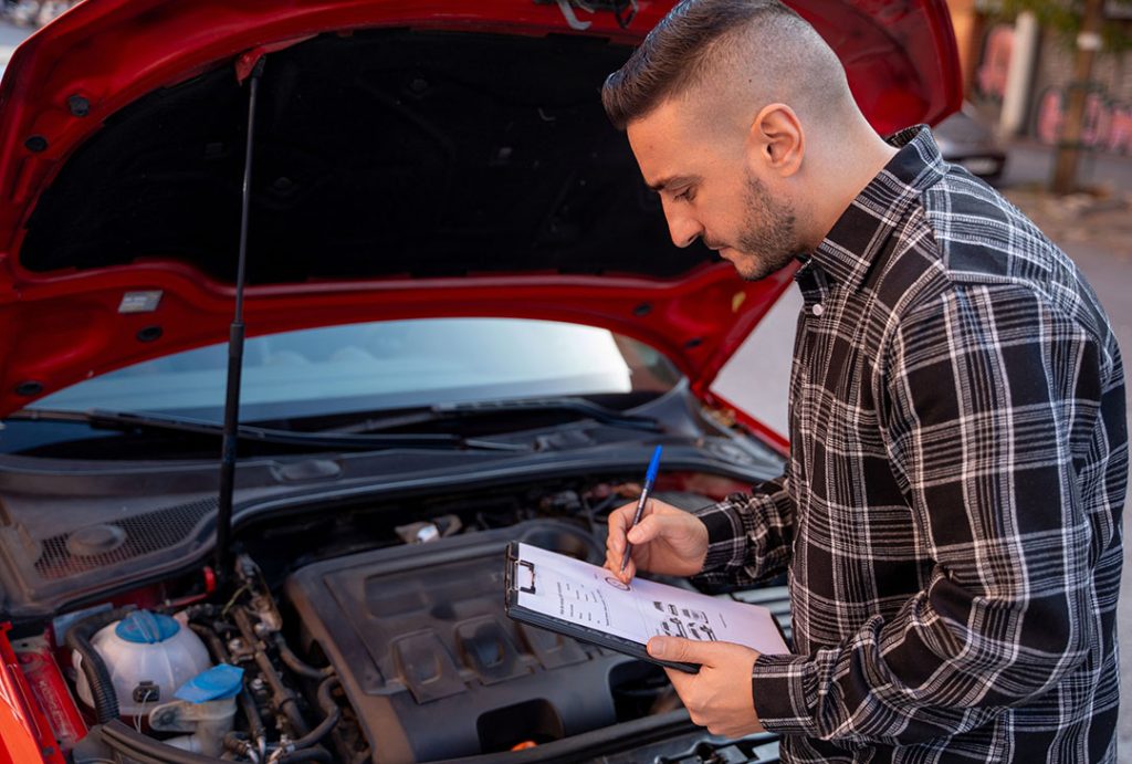 Mechanic performing an engine check as part of a vehicle inspection service Houston in a garage.