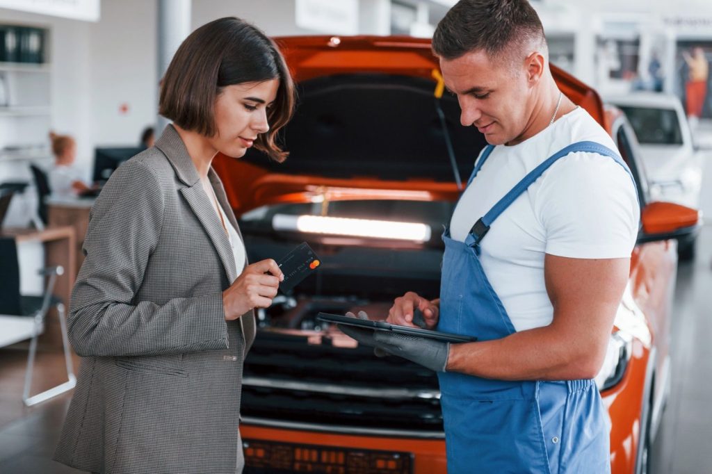 Before you buy car inspection Houston ensures transparency. Technician reviews car status as customer prepares payment.