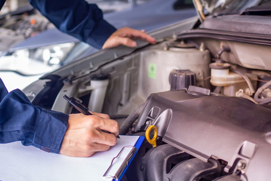 Close-up of technician writing an engine inspection report for a mobile car check Houston service.