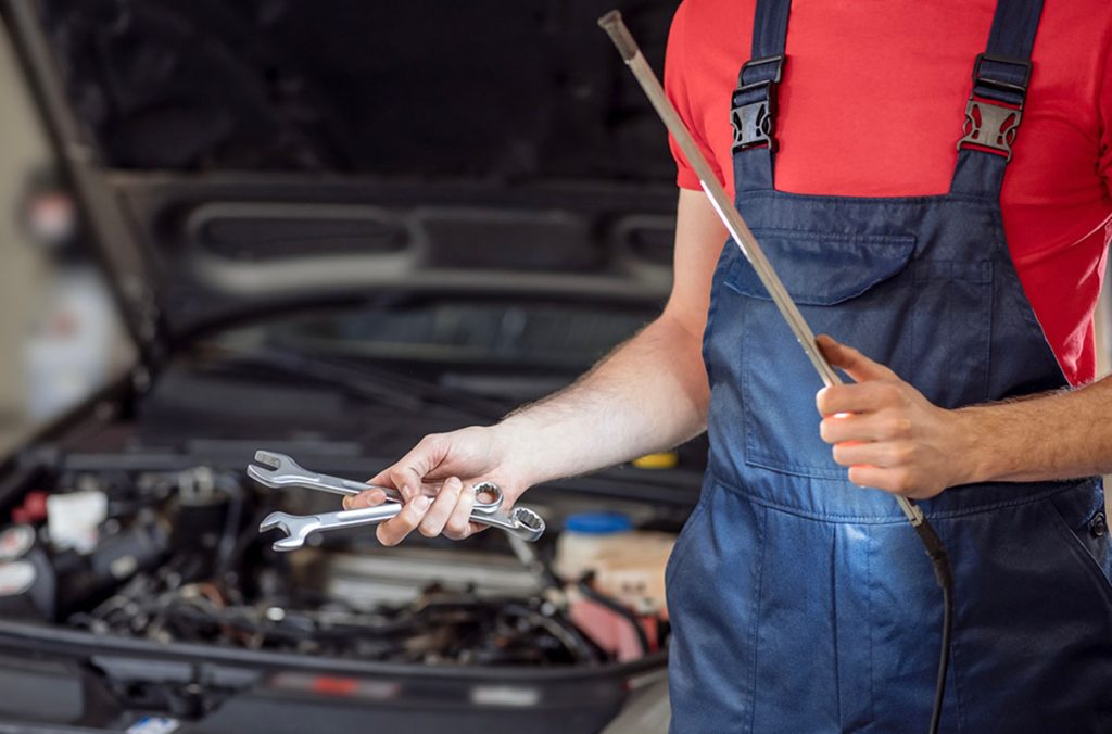 Auto technician holding professional tools needed for a thorough before you buy car inspection Houston service.