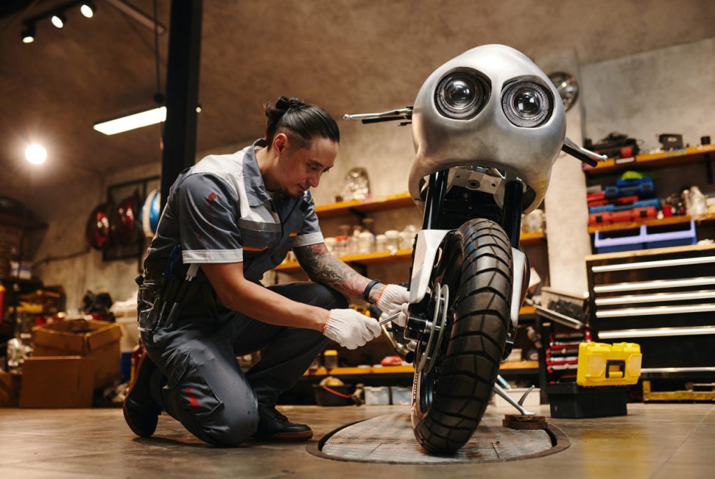 Professional mechanic performing a motorcycle inspection Houston on a custom front wheel and dual headlight bike.