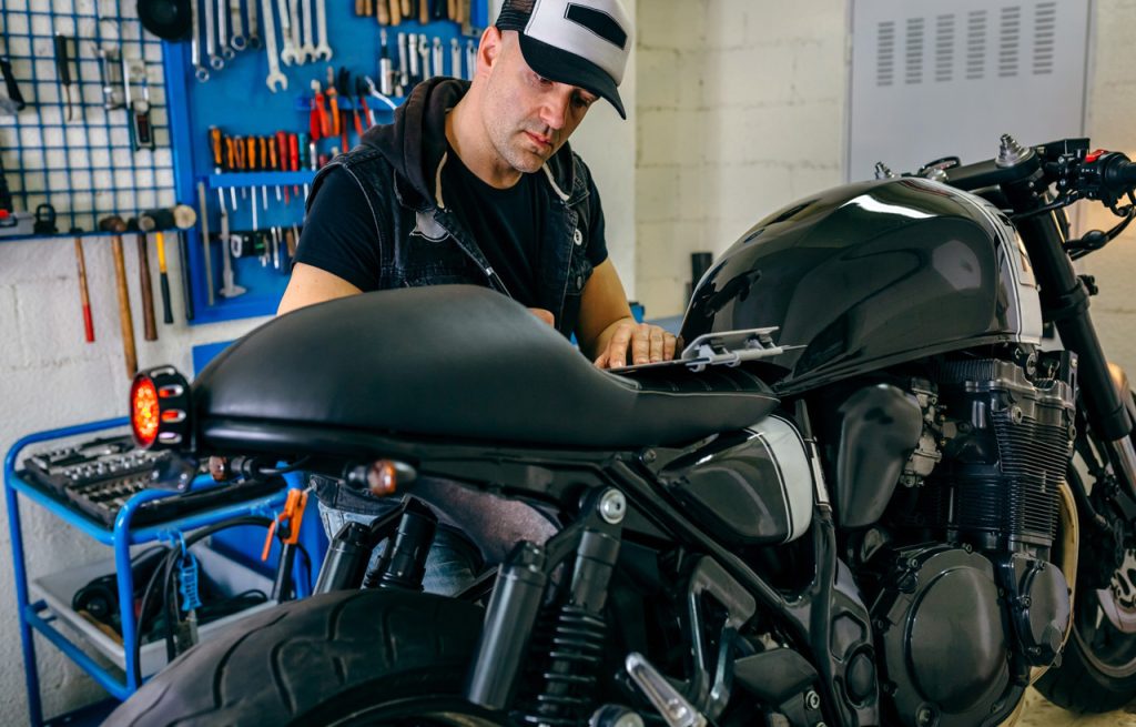 Expert technician conducting a motorcycle inspection Houston while reviewing a service checklist in a repair shop.
