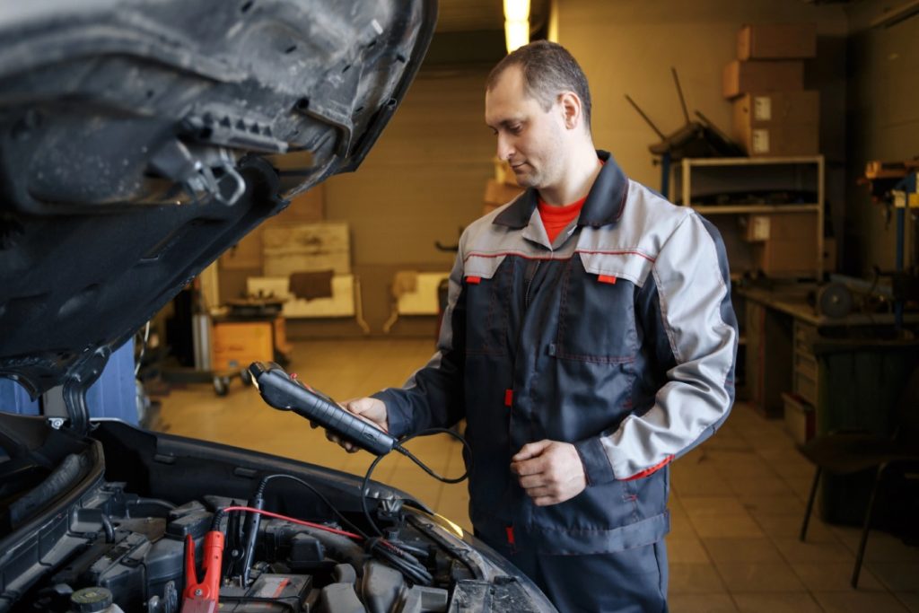 Mechanic using diagnostic tools for a battery test as part of a reliable third party inspection Houston for car buyers.