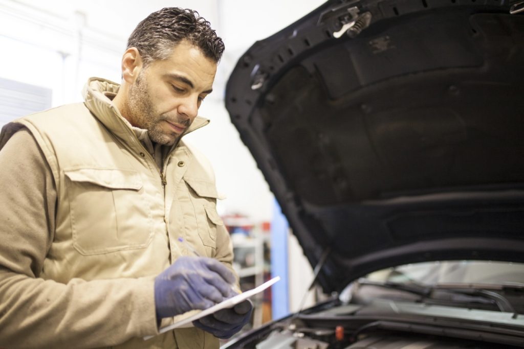 Expert technician completing an engine bay report during a comprehensive third party inspection Houston service call.