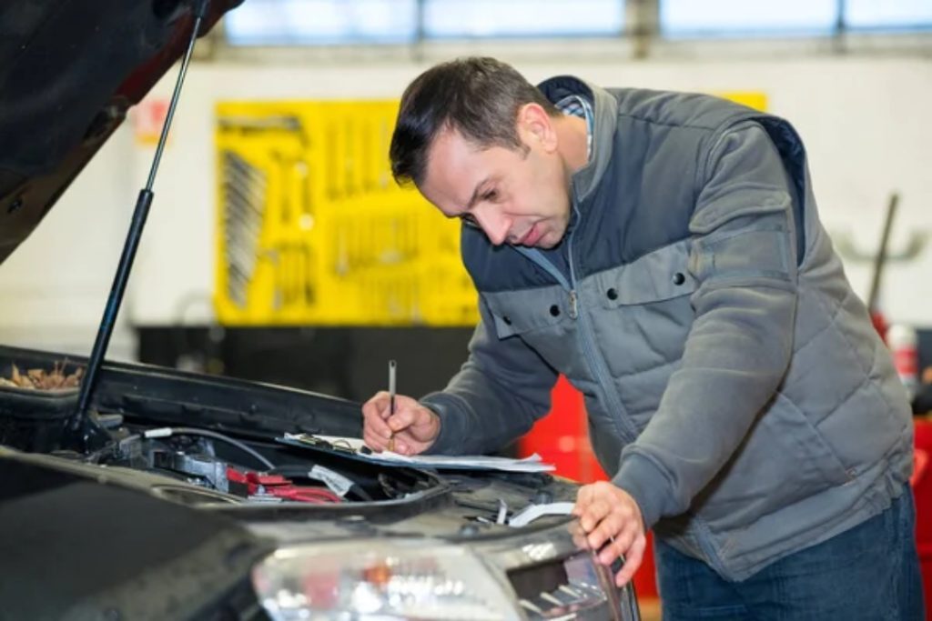 Professional mechanic performing a thorough third party inspection Houston on a car engine with a detailed checklist.